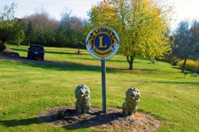 Lions River Park - Lions International sign, two lion statues, and park